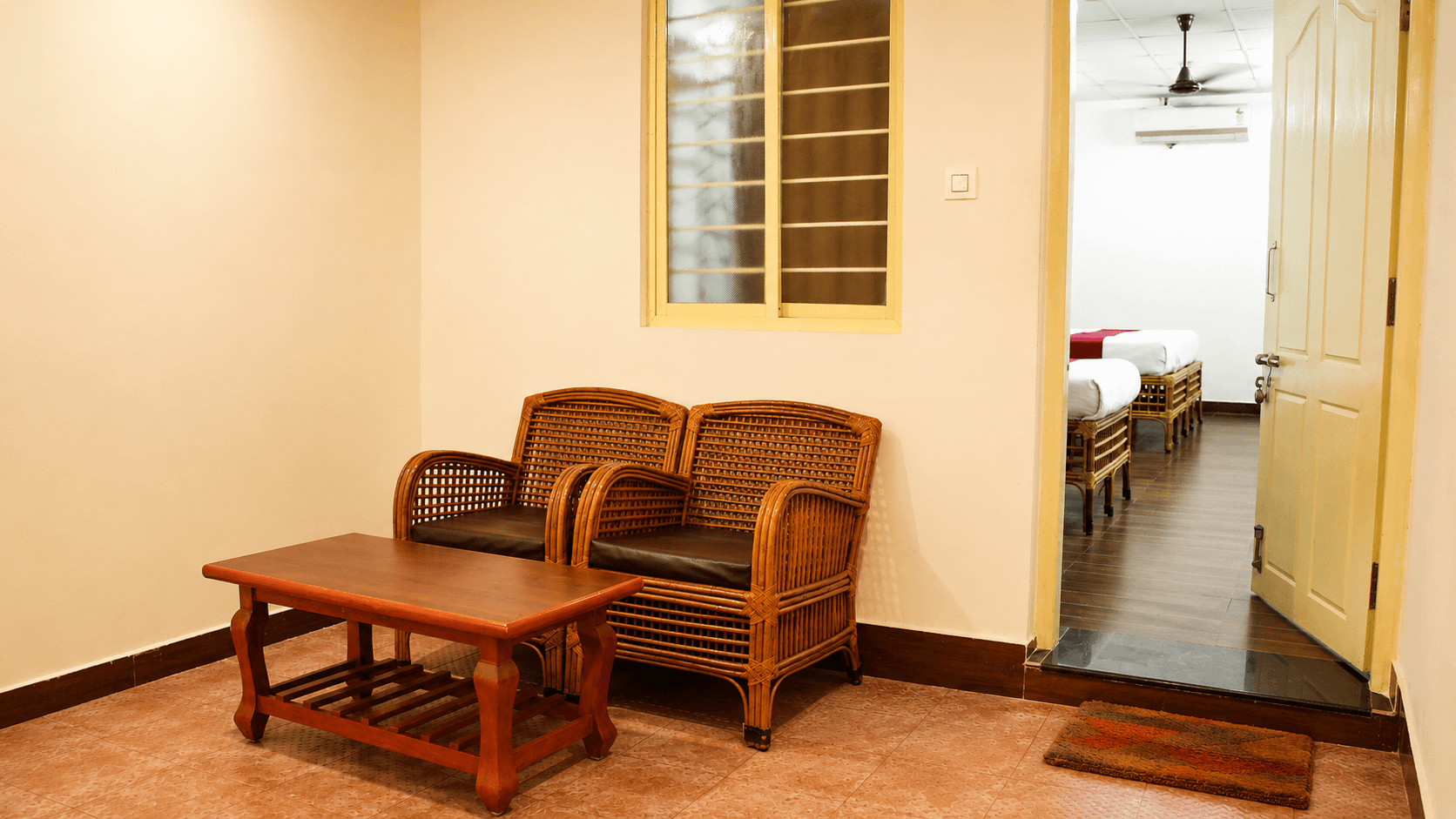 Private room veranda with rattan seating and view into bedroom at Sharmada